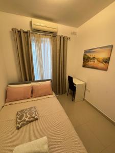 een slaapkamer met een bed, een bureau en een raam bij Belmonte Flat in Sliema