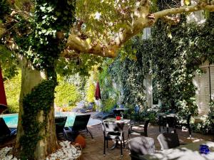 a patio with tables and chairs under a tree at CitHôtel Le Louvre in Orange