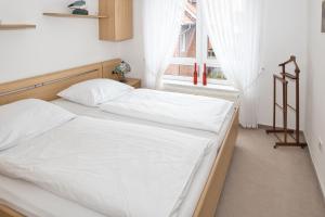 een slaapkamer met een bed met witte lakens en een raam bij Aquaris, FeWo 10 in Duhnen