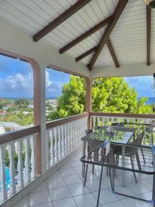 eine Veranda mit einem Glastisch auf dem Balkon in der Unterkunft L'appartement FRUIT DE LA PASSION in Le Gosier