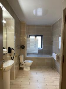 a bathroom with a tub and a toilet and a sink at Empire Hôtel in Nîmes