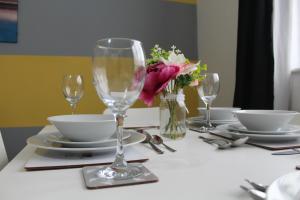 a table with glasses and plates and a vase of flowers at Clover Apartments in Hadleigh