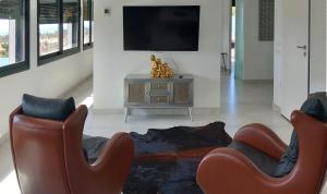 een woonkamer met twee stoelen en een televisie bij VillasRoyale Diamante in San Bartolomé