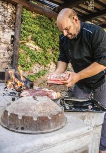 un homme cuisinant de la viande sur un grill dans l'établissement Toncevi Eco Estate, à Branik