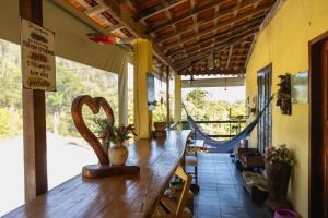 - une longue table en bois dans une chambre avec hamac dans l'établissement Hostel Yellow House MG, à Itamonte