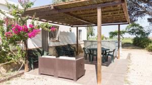 un patio con mesa y sillas bajo una pérgola en Quet - Casa rural con piscina privada en el Delta del Ebro - Deltavacaciones, en Deltebre