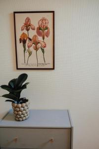 a picture on a wall with a plant on a dresser at Äspögården Bed & Breakfast in Klagstorp