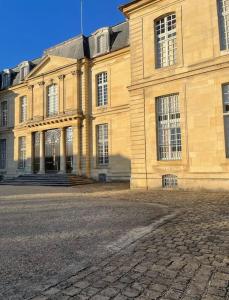 a large yellow building with a cobblestone street in front of it at Maison Entier JO 2024 Clim Disney 2 rooms in Gournay-sur-Marne