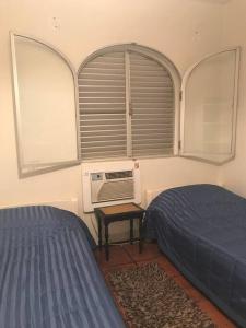 um quarto com 2 camas e uma janela em Apartamento muito charmoso na praia da Enseada no Guarujá