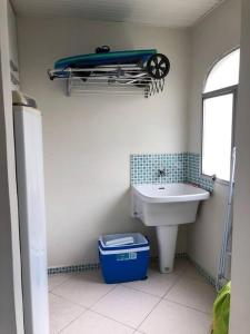 uma casa de banho com um lavatório e uma prancha de surf na parede em Apartamento muito charmoso na praia da Enseada no Guarujá