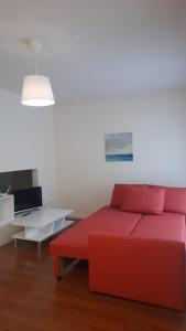 een rode bank in een woonkamer met een tafel bij Apartamento turísticos Puente Romano P1 1-C in Salamanca