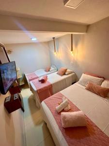 um quarto de hotel com três camas e uma televisão em Residencial Temporada Aracaju em Aracaju