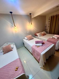 um quarto com três camas com lençóis cor-de-rosa em Residencial Temporada Aracaju em Aracaju