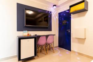 Pokój z 2 różowymi krzesłami i telewizorem na ścianie w obiekcie Motel Maresias - Radial Leste w São Paulo
