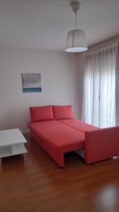een rode bank in een kamer met een raam bij Apartamento turísticos Puente Romano P1 1-C in Salamanca