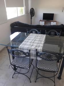 a glass table with two chairs and a couch at Bernal Alquileres in Viedma