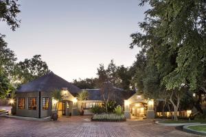 a house with a thatched roof and a driveway at Premier Hotel Roodevalley in Pretoria