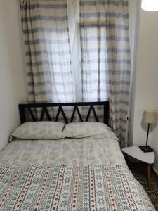 1 dormitorio con 1 cama y una ventana con cortinas en vista al mar Habitacion en apartamento compartido, en Moraira