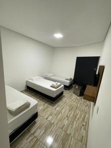 two beds in a small room with wooden floors at Hotel Hollywood in Lucas do Rio Verde