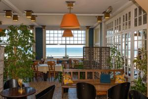 a restaurant with tables and chairs and a view of the ocean at VTF L'Hotel Des Bains in Saint-Cast-le-Guildo