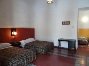 une chambre d'hôtel avec deux lits et une table dans l'établissement Hotel Principal, à Oaxaca