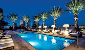 a pool with palm trees and lounge chairs at night at Hanover Post Oak in Houston