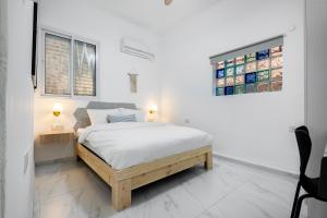 a white bedroom with a bed and two windows at Moroccan style apartment near Bahai Gardens in Haifa