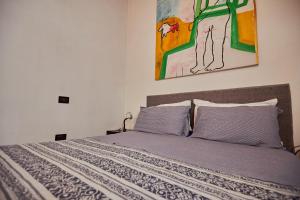 1 cama con 2 almohadas y una pintura en la pared en Bassano Porta Dieda en Bassano del Grappa