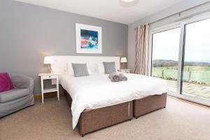 a bedroom with a large bed and a large window at Galloway View in Castle Douglas