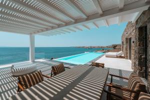 a patio with a view of the ocean and a swimming pool at Splendid Mykonos Waterfront Villa in Mikonos