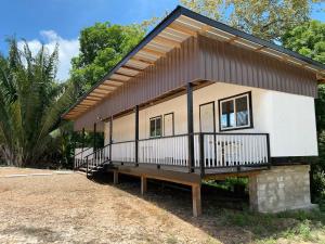 uma pequena casa branca com um telhado preto em Tropical View em Spanish Lookout