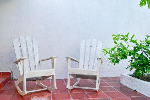 カルタヘナ・デ・インディアスにあるCARTAGENA HOSTALの白い壁の横に座る白いロッキングチェア2脚