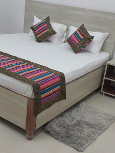 a bed with white sheets and colorful pillows on it at 5 PETALS in Varanasi