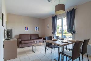 uma sala de estar com uma mesa e um sofá em Les Thermes 511 - Appt proche plage avec piscine partagée em Concarneau