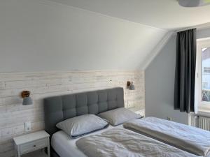 een witte slaapkamer met een bed en een raam bij Haus Mühlentrift, FeWo 05 in Döse