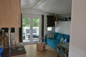 ein Wohnzimmer mit einem blauen Sofa und einer Terrasse in der Unterkunft Ferienhaus Leipzig am Schladitzer See in Rackwitz