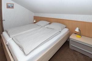 ein Bett mit weißer Bettwäsche und Kissen in einem Schlafzimmer in der Unterkunft Haus Sonneck, App 2 in Duhnen