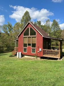 a red cabin with a porch in a field of grass at Secluded Cabin on Red Haven Farm in Irvine