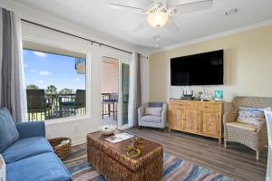 a living room with a blue couch and a tv at New Listing! Beautiful 1/1 Condo with Gorgeous Beach Views! Pool & Hot Tub!! - Shell We Dance in Galveston