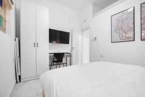 a white bedroom with a bed and a table at Moroccan style apartment near Bahai Gardens in Haifa