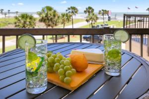 een tafel met een bord eten en twee glazen bij New Listing! Beautiful 1/1 Condo with Gorgeous Beach Views! Pool & Hot Tub!! - Shell We Dance in Galveston