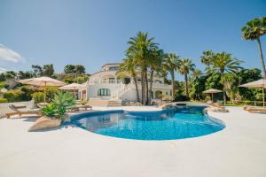 una piscina frente a una casa con palmeras en Villa La Palma, en Jávea