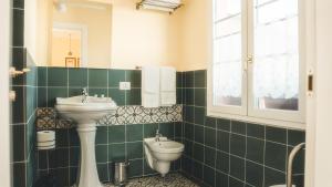 un bagno piastrellato verde con lavandino e servizi igienici di Azienda agricola La Macina a Bregnano Altre 24 foto