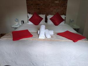 a bed with red pillows and towels on it at Bella Rosa Cottage in Clarens