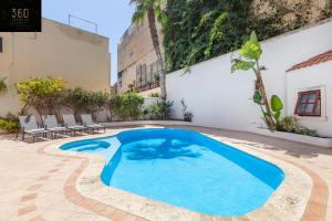 a swimming pool in a courtyard with chairs and a building at Bungalow villa with SUPER POOL AREA with WIFI & AC by 360 Estates in St Julian's