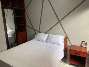 1 dormitorio con cama blanca y espejo en Acogedora casa en Cobija en Tres Puentres