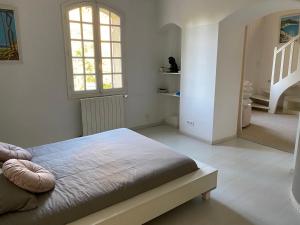 Habitación blanca con cama y escalera en Bastide de Gueissard, en Saint-Cyr-sur-Mer