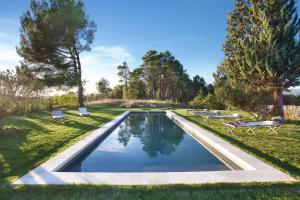 uma piscina num parque com bancos e árvores em Domaine Les Petites Vaines em Goult