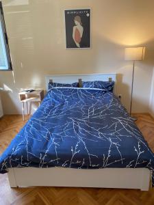 Bett in einem Schlafzimmer mit blauer Decke in der Unterkunft REA APARTMENT in Kragujevac