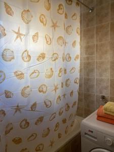 ein Badezimmer mit einem Duschvorhang mit Schalen und Seestern in der Unterkunft REA APARTMENT in Kragujevac